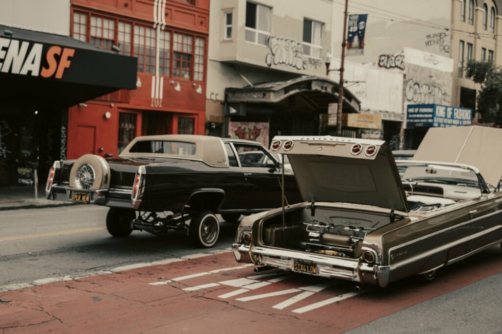 two-customized-cars-rolling-through-a-city-street
